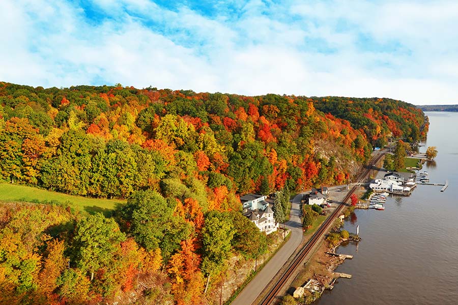 About Our Agency - View of the Hudson Valley with Fall Foliage Against a Cloudy Blue Sky